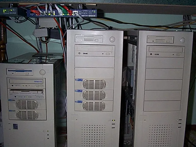 Three beige computer towers beneath network equipment